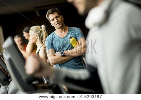 Young Man Drinking Bottle Of Water On Threadmill In Gym