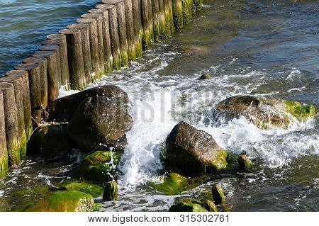 Sea Tidal Bore. Waves Break On Stones Overgrown By Moss And Algae. Beautiful Seascape.