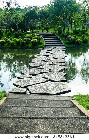 Stone Pathway Across The Pond In The Park
