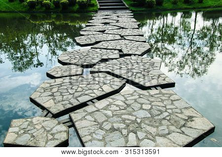 Stone Pathway Across The Pond In The Park