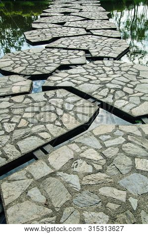 Stone Pathway Across The Pond In The Park