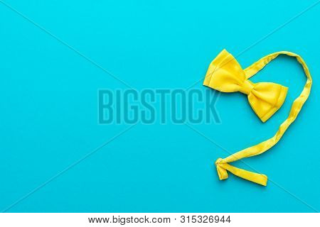 Top View Photo Of Yellow Silk Bow Tie Over Turquoise Blue Background With Copy Space. Minimalist Fla