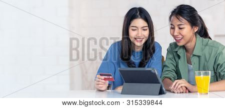 Candid Of Young Attractive Asian Two Girls Sitting At Home Holding Discount Credit Card In Hand Payi