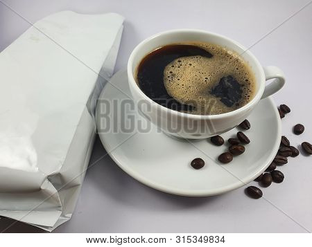 Black coffee in white cup, coffee beans on old wooden texture background. Selective focus