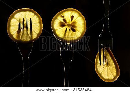 Collage Of Three Slices Of Lemons On The Fork On Dark Black Background. Silhouette Of A Fork In The 