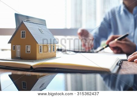 House Model And Business Insurance Authorities Showing An Insurance Policy And Dealing The Policyhol