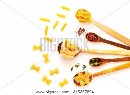 Wooden Spoons With Pasta And Spices On White Isolated Background. The Concept Of Italian Cuisine. Cl