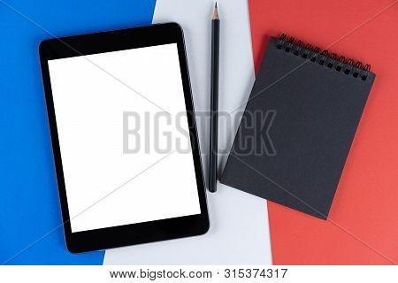 Black Tablet, E-book, Notebook And Pencil Is On Flag France. Texture French National Flag Colored Ca