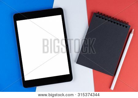 Black Tablet, E-book, Notebook And White Pencil Is On Flag France. Texture French National Flag Colo
