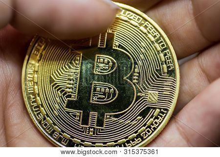Golden Bitcoin In A Man Hand, Digitall Symbol Of A New Virtual Currency