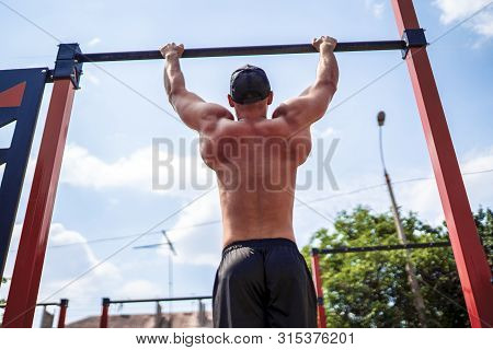 Brutal Athletic Man Making Pull-up Exercises On A Crossbar At Outdoor Streeet Gym.