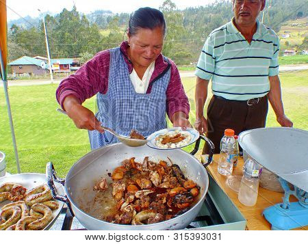 Cuenca, Ecuador - Octobre 7, 2018: Indigenous Woman Vendor Prepares In Big Bowl Pork Fry-up Or Frita