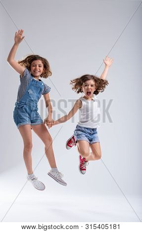 Exuberant Young Sisters Jumping For Joy