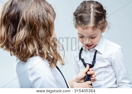 Older Girl Helping Her Young Sister Tie Her Necktie Of Her School Uniform In An Over The Shoulder Vi