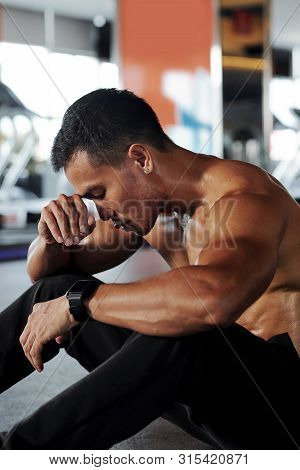 Young Asian Man Sitting On The Floor With Eyes Closed And Resting After Exhauting Training