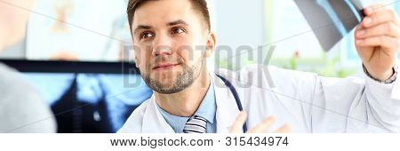 Portrait Of Smiling Doctor Talking With Patient About Good Snapshot Results. Doc Looking At Visitor 