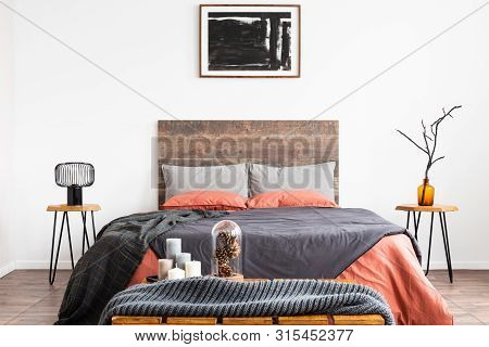 King Size Bed With Orange And Grey Bedding Between Two Wooden Nightstand With Lamp And Vase