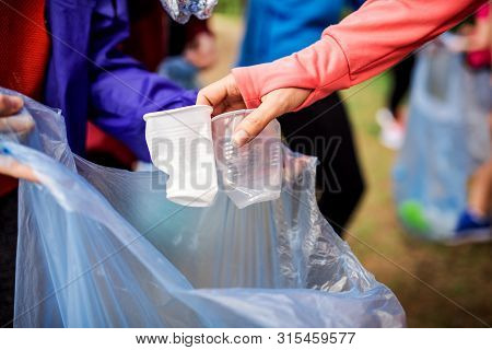 Midsection Of Group Of Fit People Picking Up Litter In Nature, A Plogging Concept.