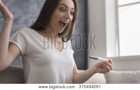 Yes, I Am Pregnant. Happy Young Lady Discovering Positive Result On Pregnancy Test, Home Interior, C