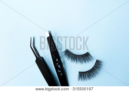 False Eye Lashes, Black Tweezers On Blue Background With Copy Space, Mockup. Beauty Concept - Tools 
