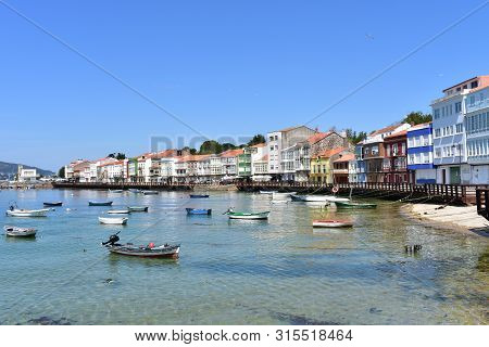 Mugardos, Spain. August 2, 2019. Small Fishing Village With Boats And Colorful Houses. Blue Sky, Sun
