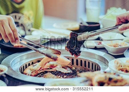 People Grilling Meat On A Smokeless Barbecue Grill In A Restaurant.