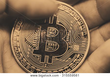 Golden Bitcoin In A Man Hand, Digitall Symbol Of A New Virtual Currency