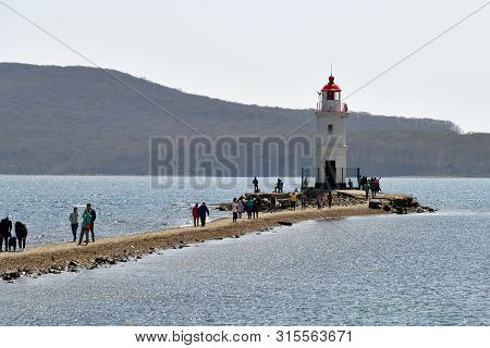 Vladivostok, Russia - April 28, 2019: People Visit White Lighthouse With Red Roof On Tokarev Cat. Bo