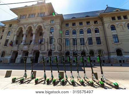 Bucharest, Romania - August 05, 2019: Several Lime-S Electric Scooters are parked on a sidewalk across the road from the Bucharest City Hall. This image is for editorial use only.