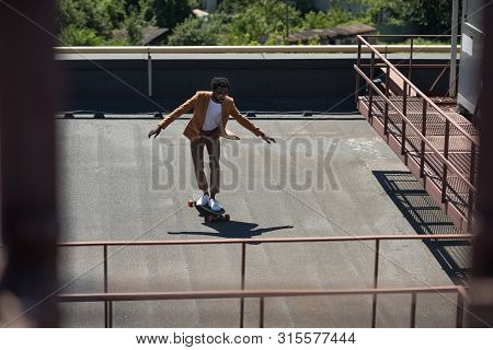 Selective Focus Of African American Businessman Lonboarding On Sunny Rooftop