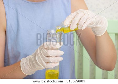 Young Beautiful Girl Shows How To Make Slime.. Hands In Medical Gloves And A Flask With A Yellow Liq