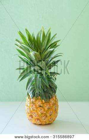 Pineapple On White Wooden Table Over Neo Mint Background. Tropical Summer Vacation And Beach Party.