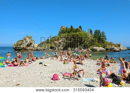 Taormina, Italy - June 20, 2019: Bathers On The Beach Of Taormina With Isola Bella Island On The Bac