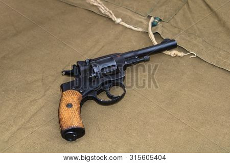Wwii Black Revolver With Wooden Handle Rests On Green Canvas