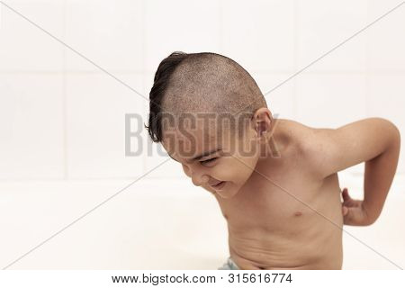 Six-year Boy At Haircutting At Home. Father Cut Half Of The Son's Hair Off At The Bathroom