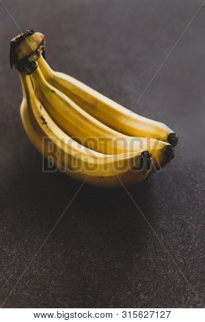 Three Bananas On Dark Background Shot At Shallow Depth Of Field