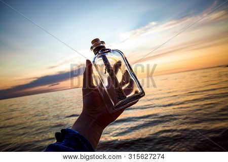 Message in the bottle against the Sun setting down