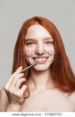 Cheerful Beauty. Portrait Of Cute Young Woman With Long Red Hair Painting Lips With Lipliner And Loo