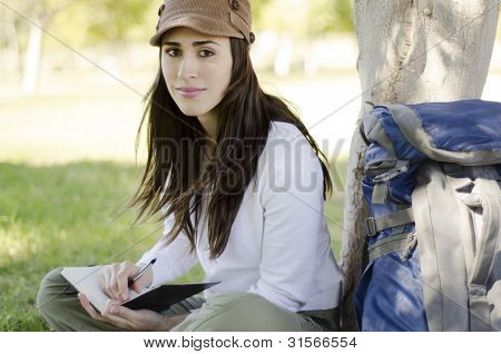 Escritura en diario de viaje de la mujer joven
