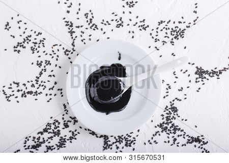Black Tahini Sauce And Black Sesame Seeds On White Background. Natural Paste Made From Sesame Seeds.