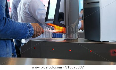 Close-up View Of People Passing Through A Turnstile Showing Some Document With Barcode In Building. 
