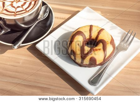 Chocolate-coated Donuts In A White Plate On A Wooden Floor