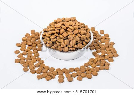 Full Cup With A Slide Of Dry Pet Food Isolated On White Background. Metal Bowl For Cat Or Dog. The C