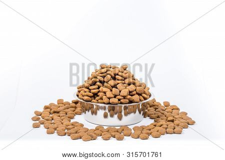 Full Cup With A Slide Of Dry Pet Food Isolated On White Background. Metal Bowl For Cat Or Dog. The C