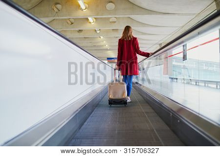 Young Woman In International Airport With Luggage On Travelator