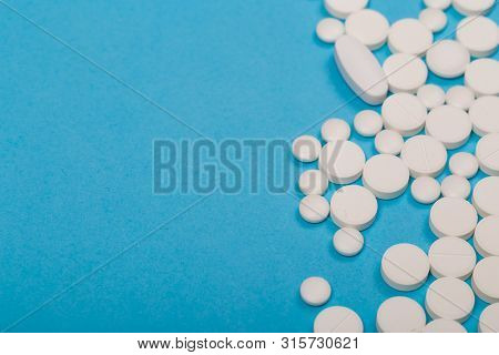 Pharmacy Theme. White Different  Pills And Capsules On The Blue Surface. Closeup