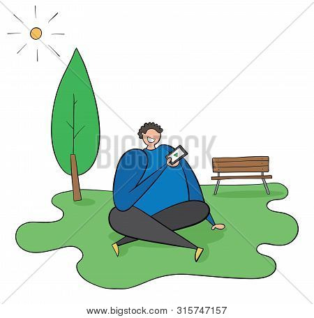 The Man Is Sitting On The Grass In The Park, The Weather Is Sunny, He Has The Mobile Phone In His Ha