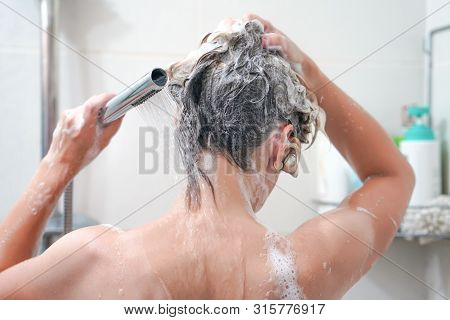 Woman Washing Her Hair With A Lot Of Foam Inside A Shower. Back View Of Young Woman Washing Her Hair