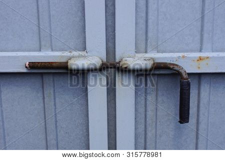 One Large Iron Deadbolt On A Gray Metal Gate