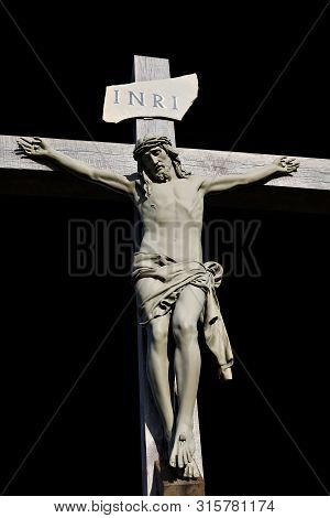 Concrete Crucifix Of Jesus Christ Isolated On Black And Plaque Attached With Inri Concept Of Passion